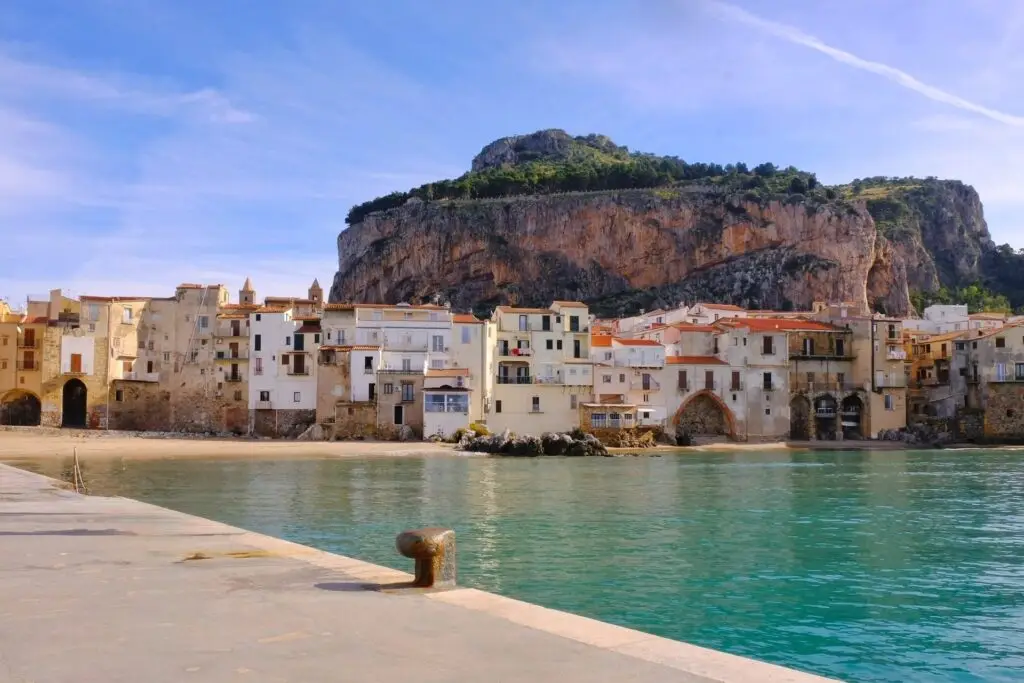 View of Cefalù's seaside houses and La Rocca under a blue winter sky