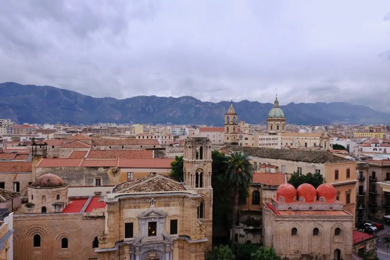 Rooftop view of Palermo with domes and church towers under grey skies