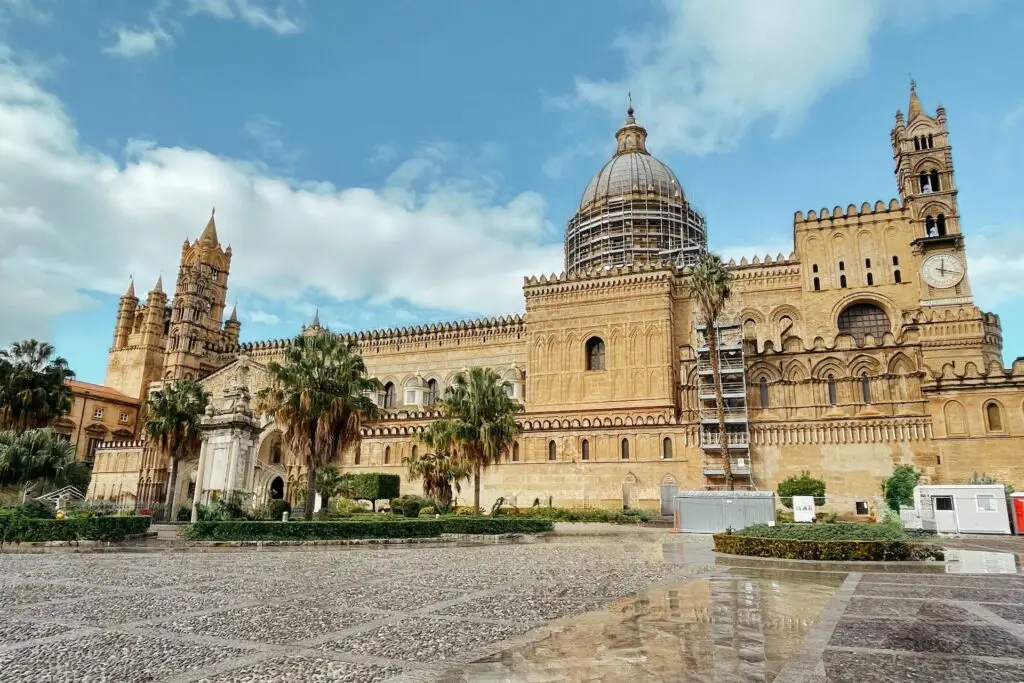 Exterior view of Palermo Cathedral under blue skies, showcasing its mix of Norman and Gothic architectural styles